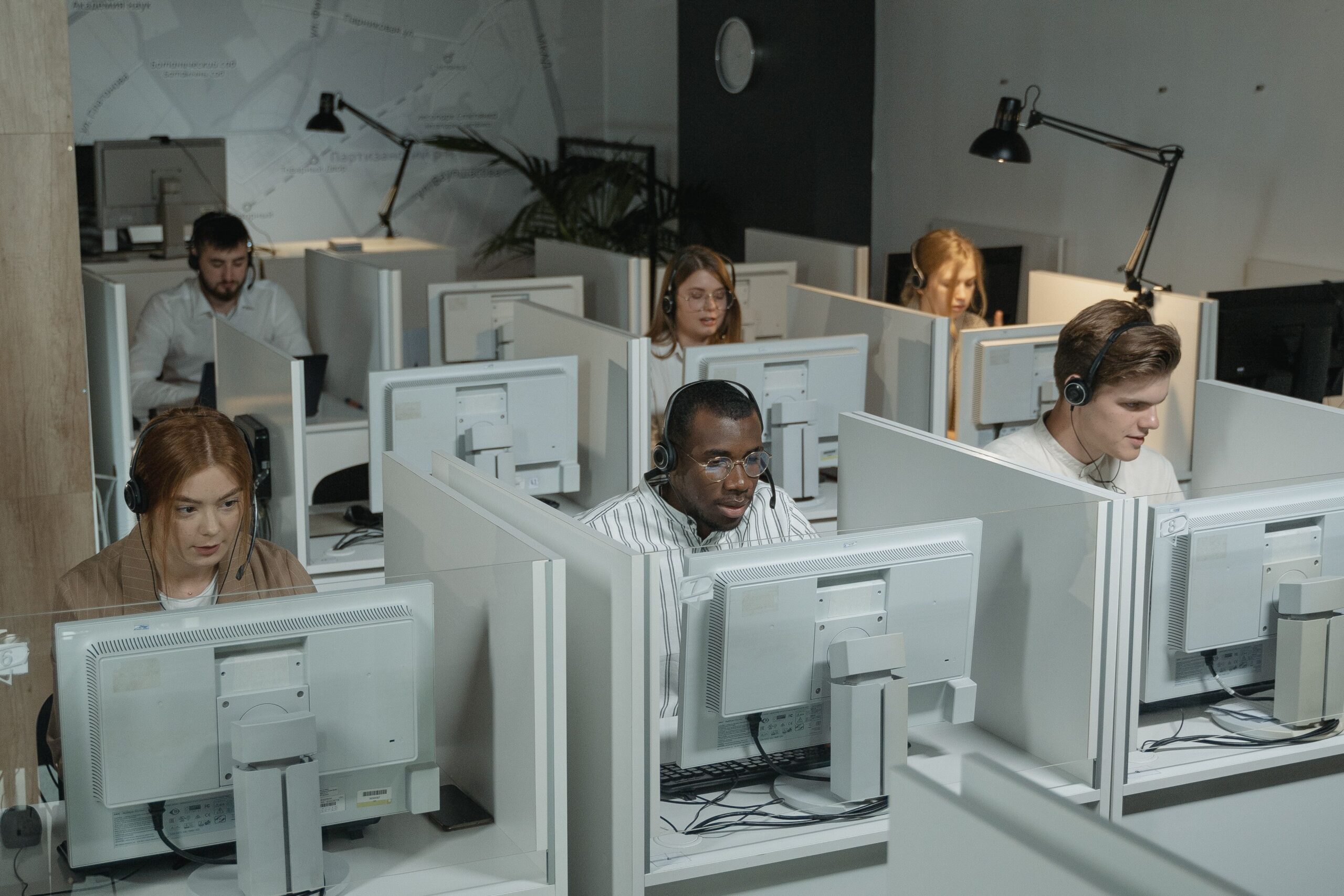 Agents wearing headsets work at computers in cubicles, a typical BPO and call center team handling customer support calls.