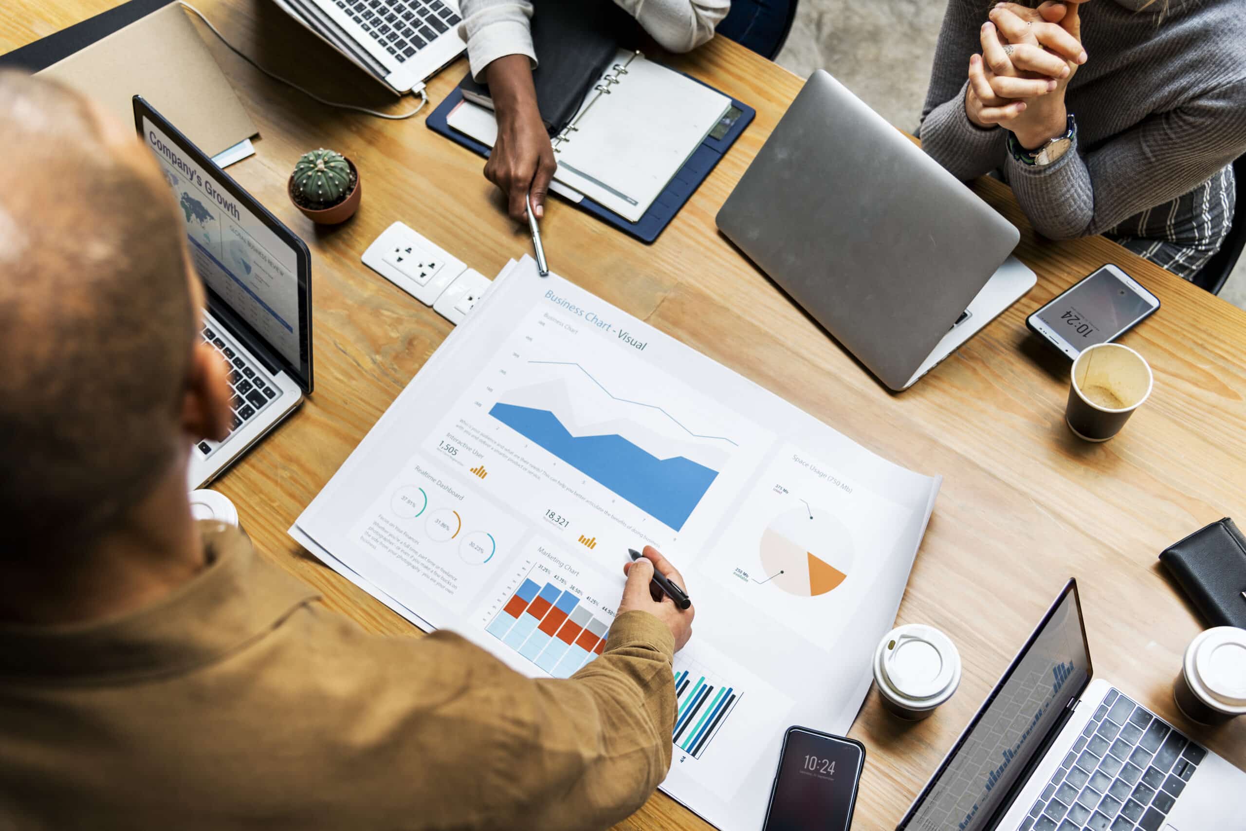 Team reviewing printed business charts and graphs on a desk, tracking campaign results for performance marketing decisions.