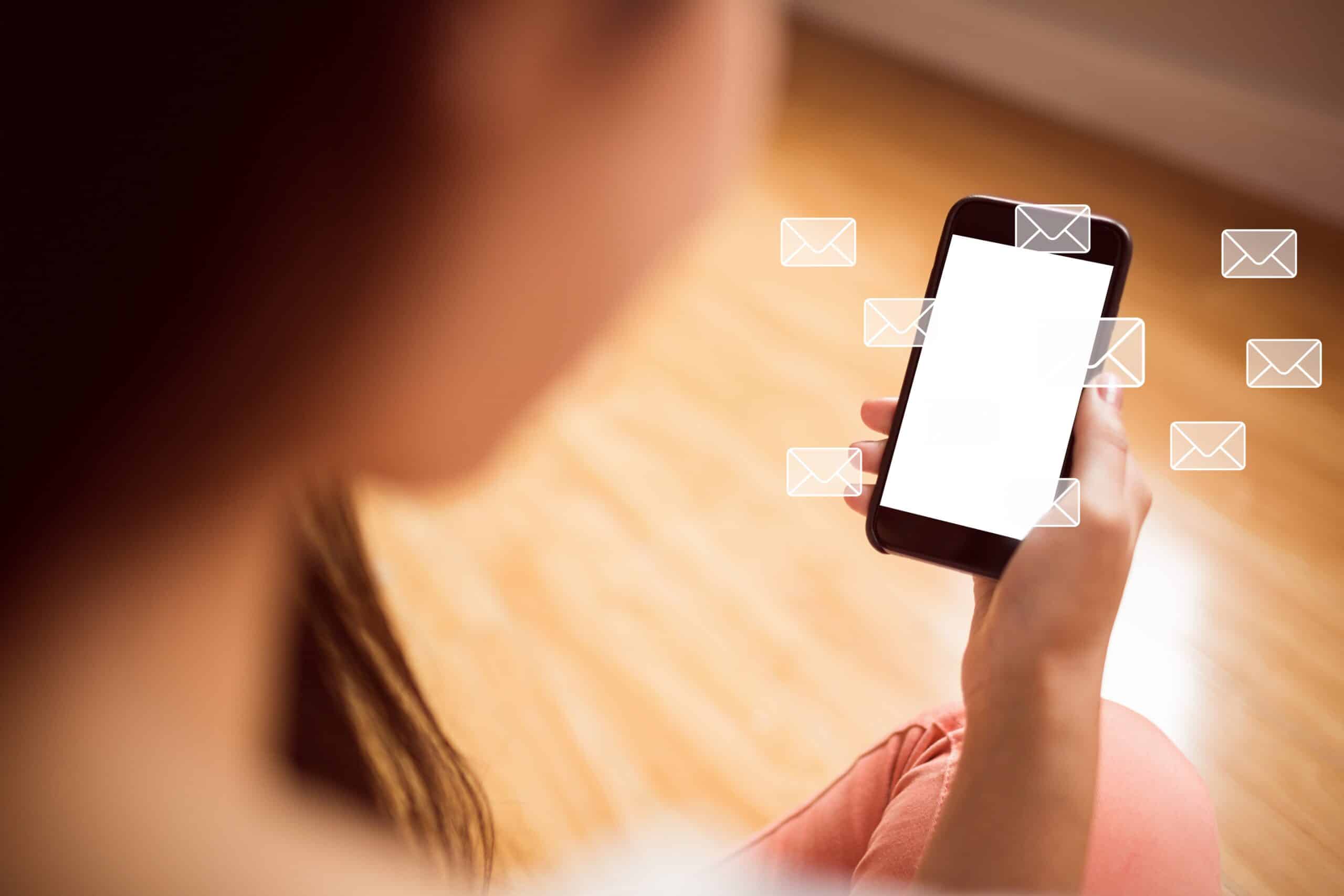 Woman holding a smartphone as message icons float around it, showing how SMS marketing reaches customers directly on mobile.